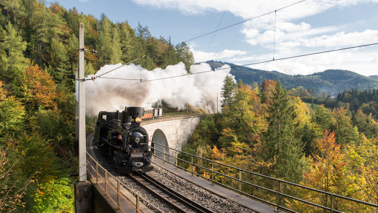 Dampfzug Mh.6, © NÖVOG/Gregory Historische Dampflok fährt über Viadukt durch herbstlichen Wald