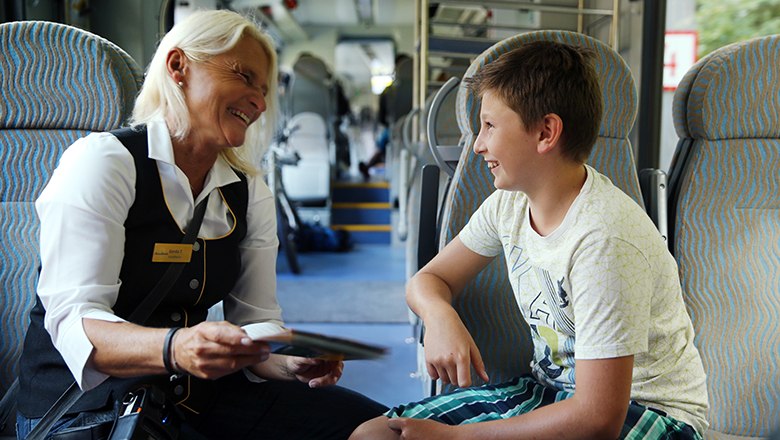 Schaffnerin und Kind lachen gemeinsam im Zug