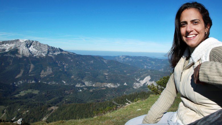 Liftfahrt zum Gipfel der Gemeindealpe, © weinfranz.at Frau sitzt auf einem Berg mit Blick auf eine Berglandschaft.
