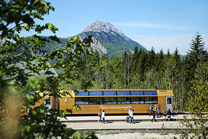 Goldene Panoramawagen vor dem &Ouml;tscher unter blauem Himmel.