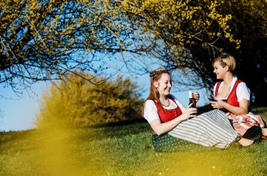 zwei Frauen sitzen mit Dirndl in der Wiese