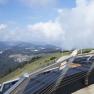 View from the Terzerhaus of a mountainous landscape with clouds and a railing in the foreground.