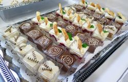 Platte mit verschiedenen dekorierten Petit Fours und kleinen Kuchenstücken.