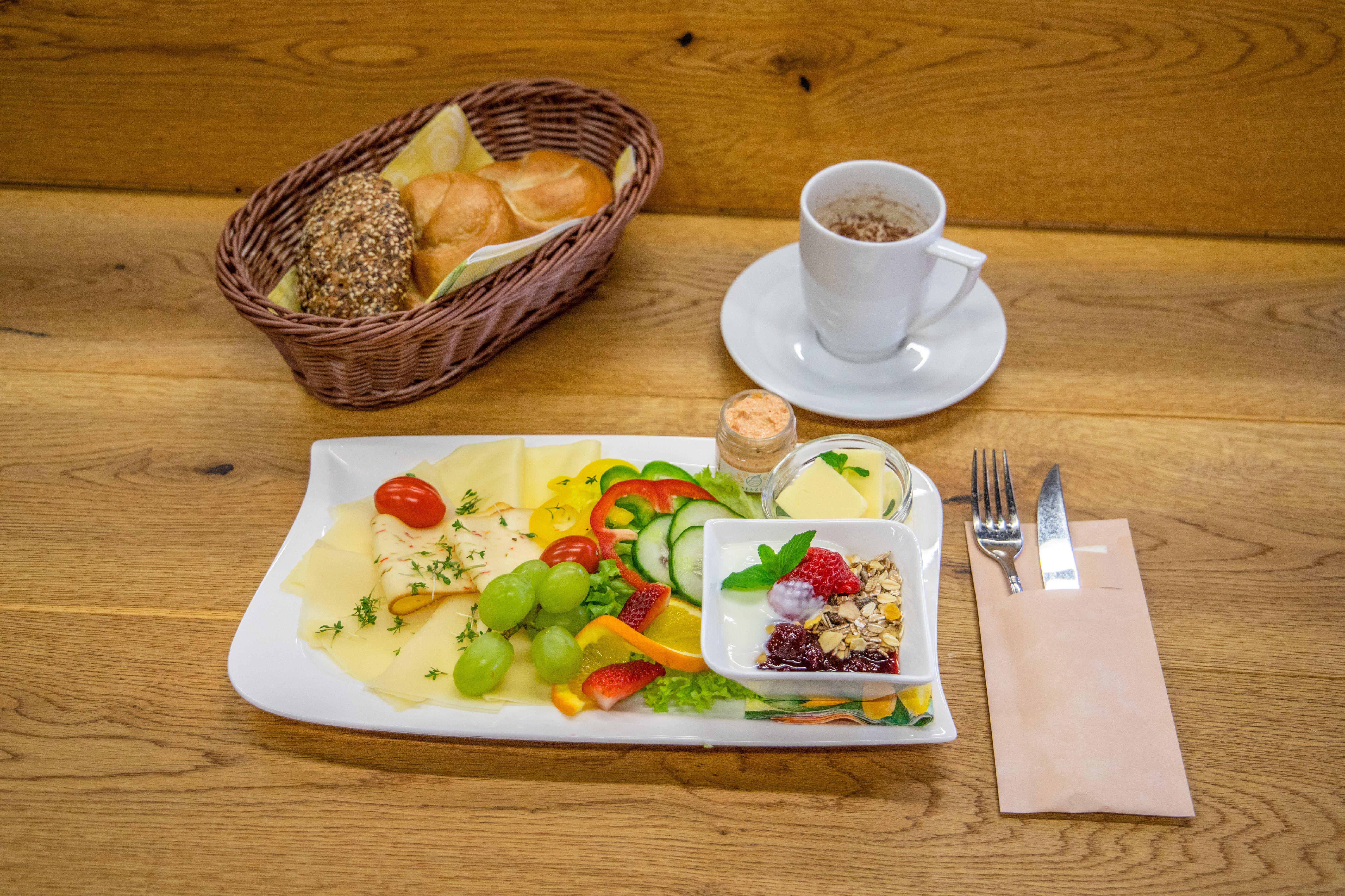 Frühstück mit Brot, Käse, Gemüse, Obst und Kaffee.