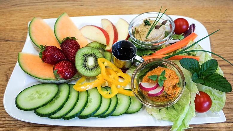 Bunte Obst- und Gemüseplatte mit verschiedenen Aufstrichen.