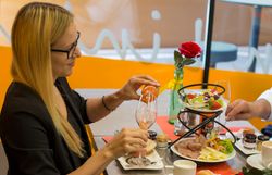 Frau beim Essen an einem reich gedeckten Frühstückstisch.