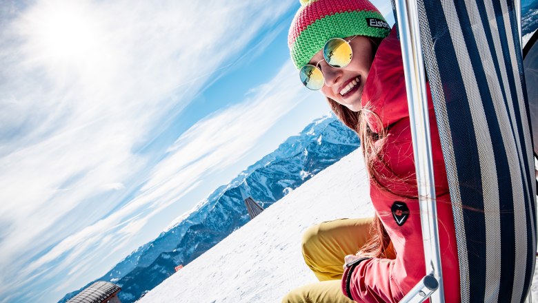 Frau sitzt in Liegestuhl in Winterlandschaft