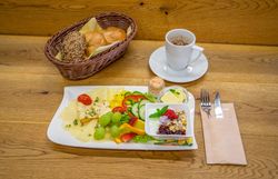 Frühstück mit Brot, Käse, Gemüse, Obst und Kaffee.