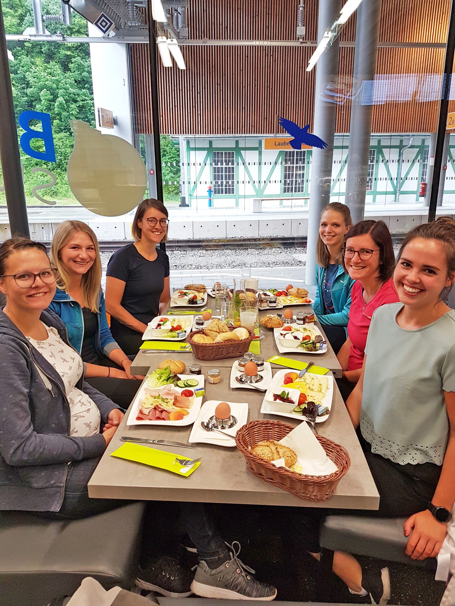 Gruppe von Frauen beim gemeinsamen Frühstück an einem langen Tisch.