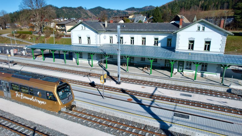 Bahnhof mit Zug und umliegender Landschaft.