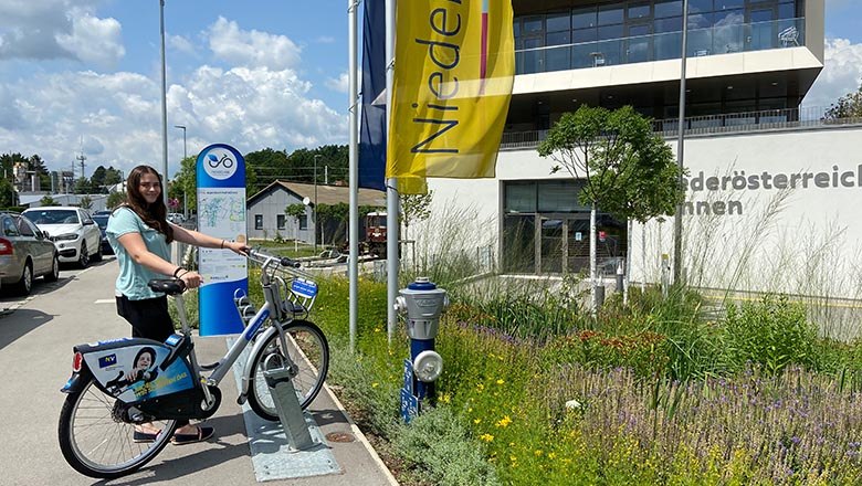 Mädchen steht vor Betriebsstätte Alpenbahnhof vor Nextbike-Station