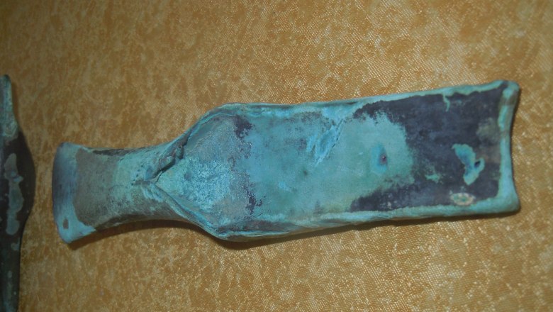 An old, oxidized metal tool on a yellow background.