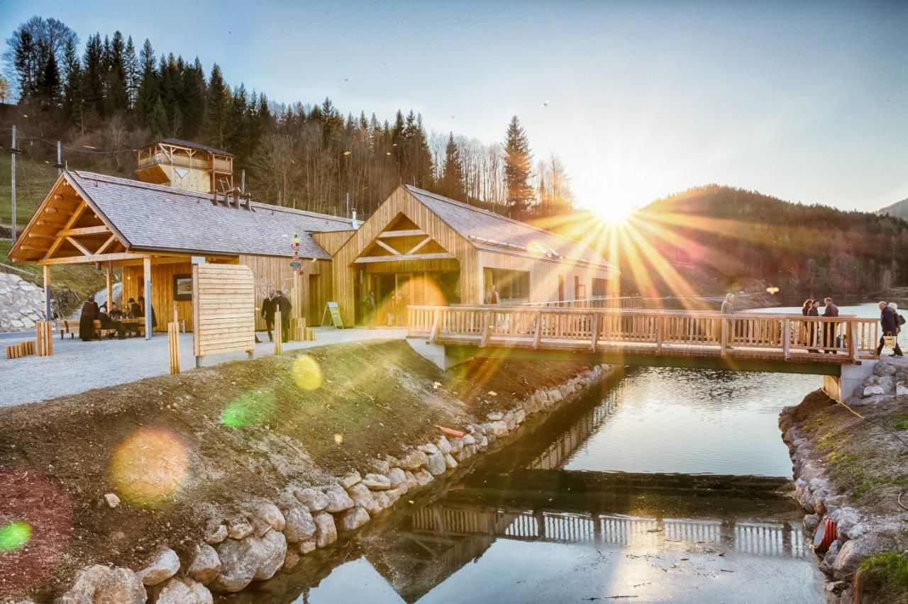 Ötscher-Basis Wienerbruck mit Holzgebäuden und Brücke bei Sonnenuntergang.