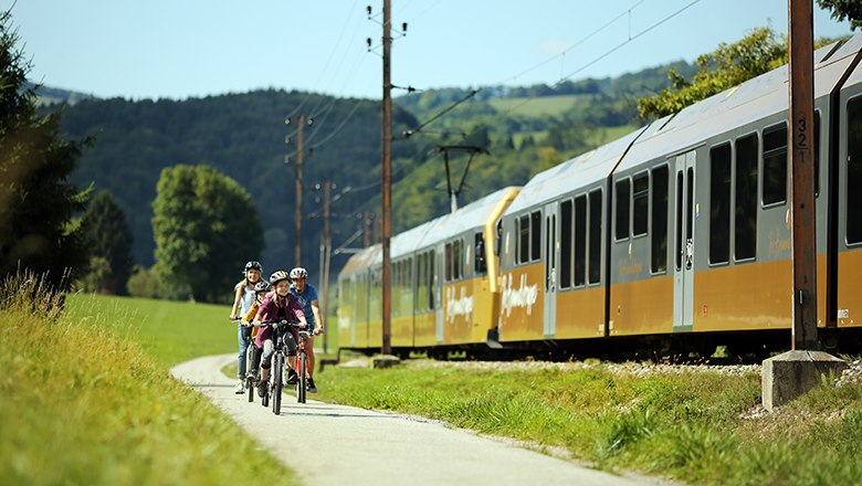 Radfahrer fahren neben Mariazellerbahn 