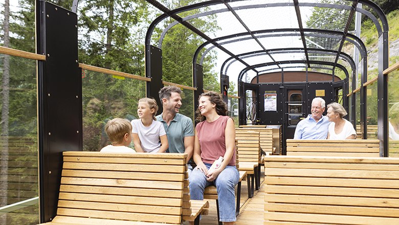 Familie sitzt im Aussichtswagen und genießt die Landschaft