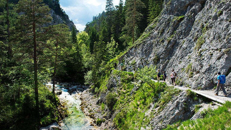 Wanderer gehen neben den Felsen, unter ihnen fließt Wasser