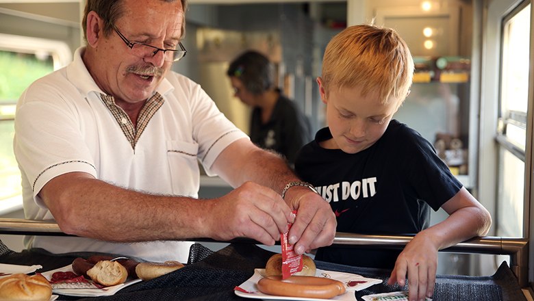 Vater und Sohn essen ein Paar Würstel