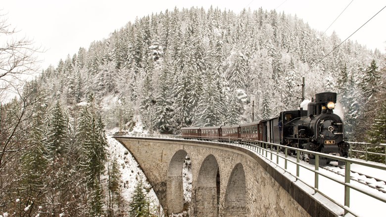 Dampflok auf Viadukt umgeben von Schnee