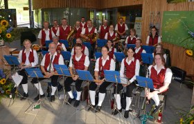Trachtenmusikverein mit wei&szlig;en Hemden, roten Gelit und langen wei&szlig;en Socken. Die Musiker haben verschiedene Instrumente in der Hand